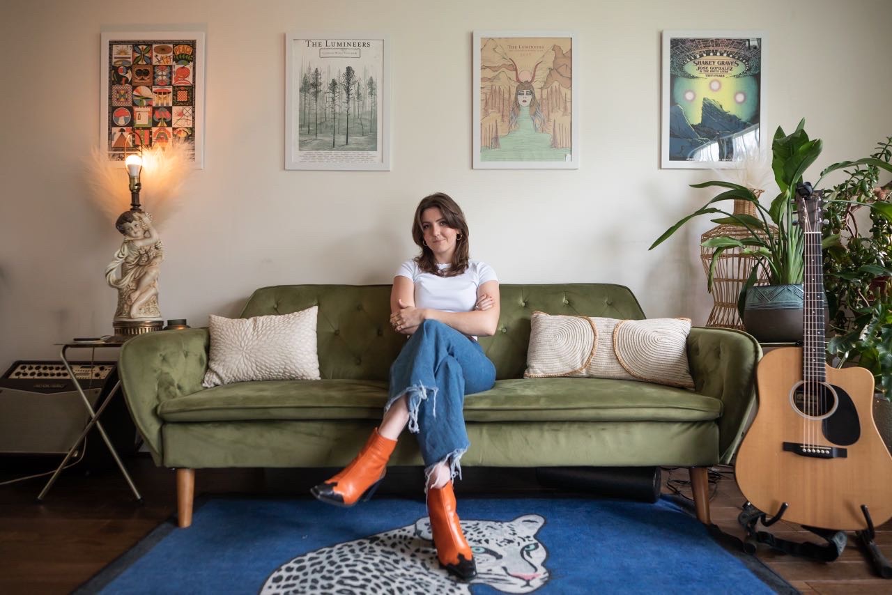 WBTV programmer Emmy McDonnell sitting on a couch in her apartment.